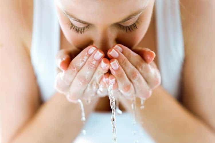 what to do before a facial steam showing woman cleansing her face