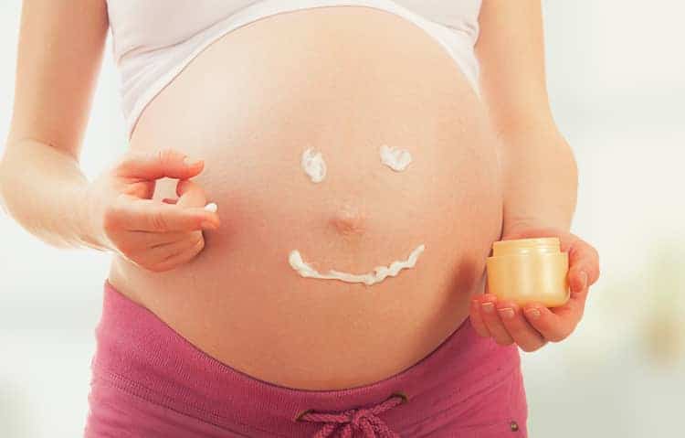 pregnancy safe alternatives to retinol - pregnant woman's belly with cream in smiley face format