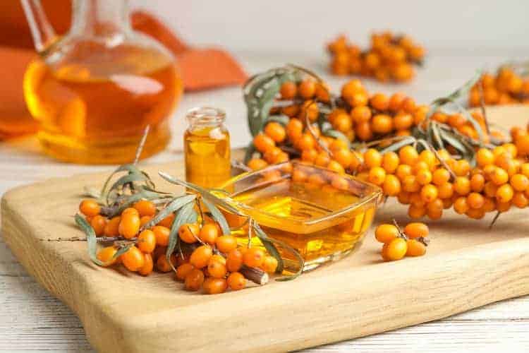 sea buckthorn carrier oil for skin and fresh berries on cutting board